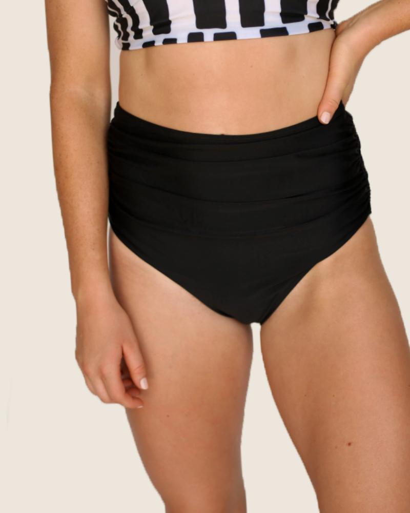 A studio image of a women wearing black high rise swimsuit bottoms with ruched detailing.